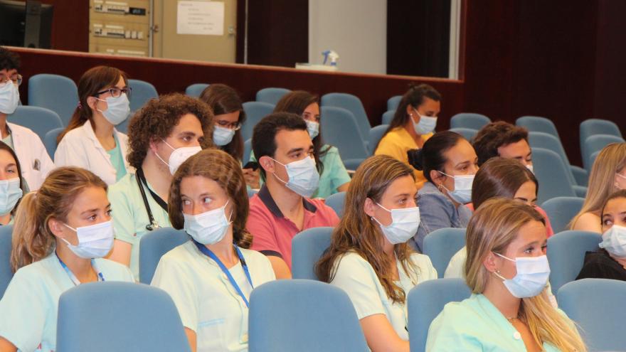 Personal médico con mascarilla y sentado en un salón de actos