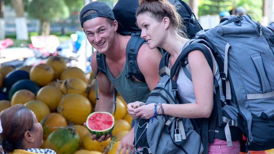 Dos mochileros comprando una sandia en un puesto callejero