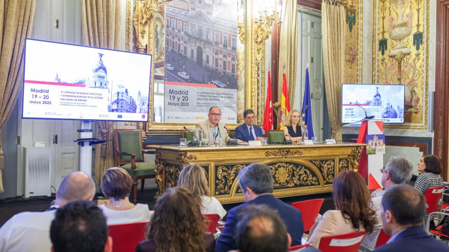 Vista del estrado de la sala plenaria con autoridades de la Clausura, pantallas, banderas y trasera conmemorativa con Puerta del Sol