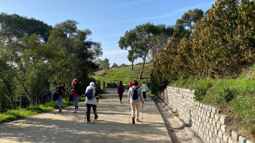 grupo de personas paseando de espaldas por un camino de tierra dentro de un parque