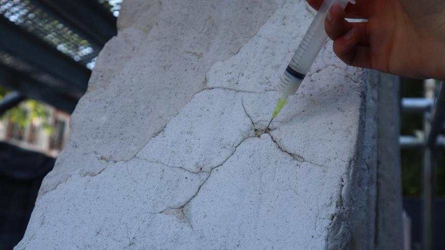 restauradora inyectando material con una aguja sobre unas grietas