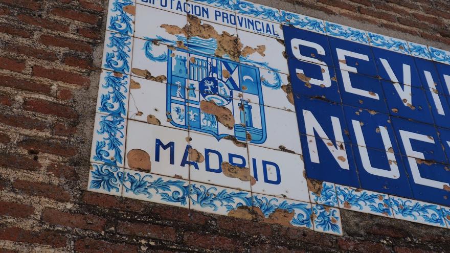 Escudo de azulejos azul sobre fondo blanco rodeado de cenefa de flores