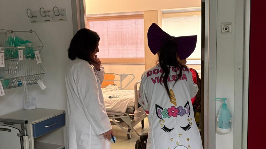 Una médica de espaldas junto con una mujer caracterizada de payasa