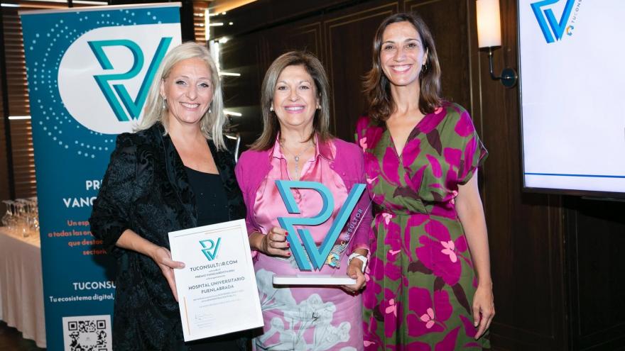 Tres mujeres posan frente junto con un diploma y un premio