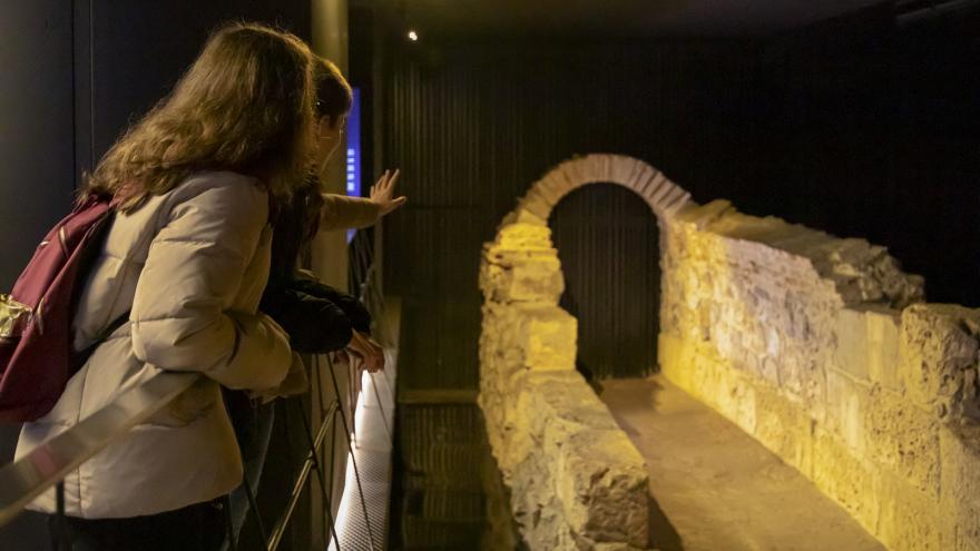 jóvenes señalan un arco de piedra
