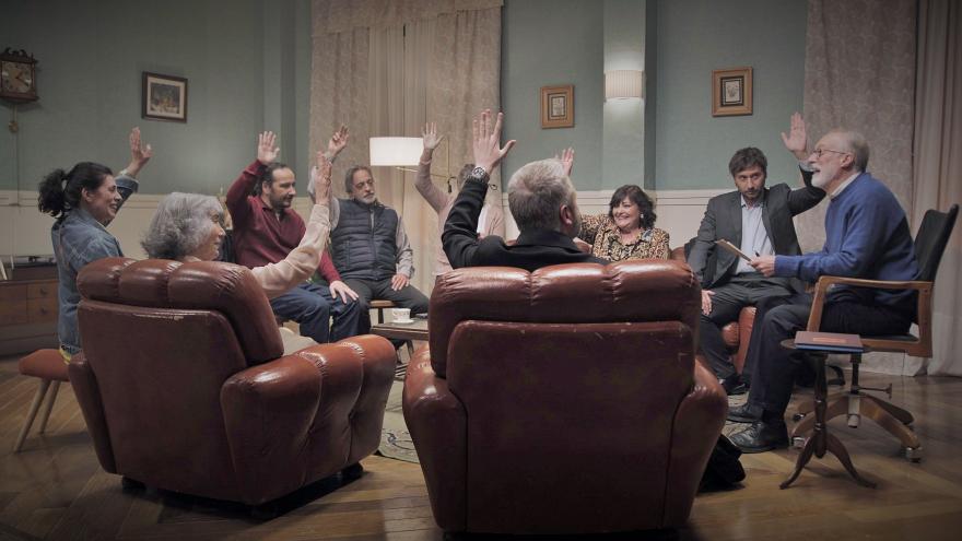 Un grupo de personas levantando la mano alrededor de una mesa