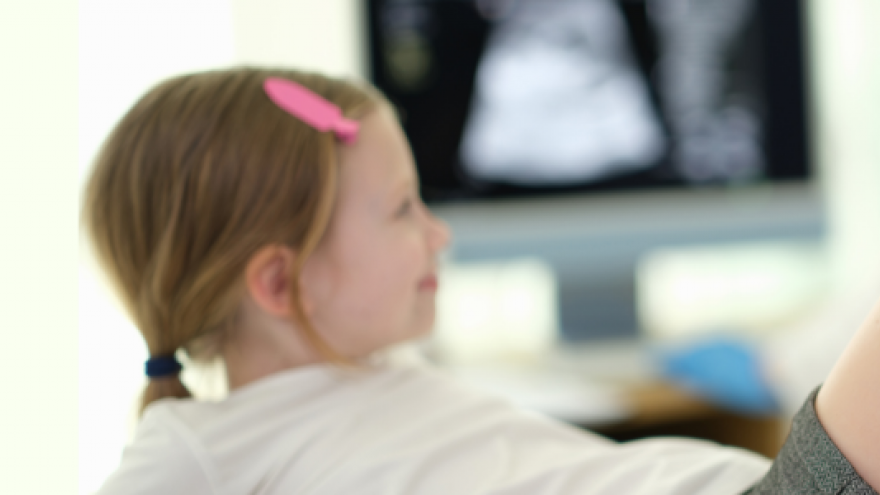 niña en consulta tumbada con pierna doblada mientras la examina la médica