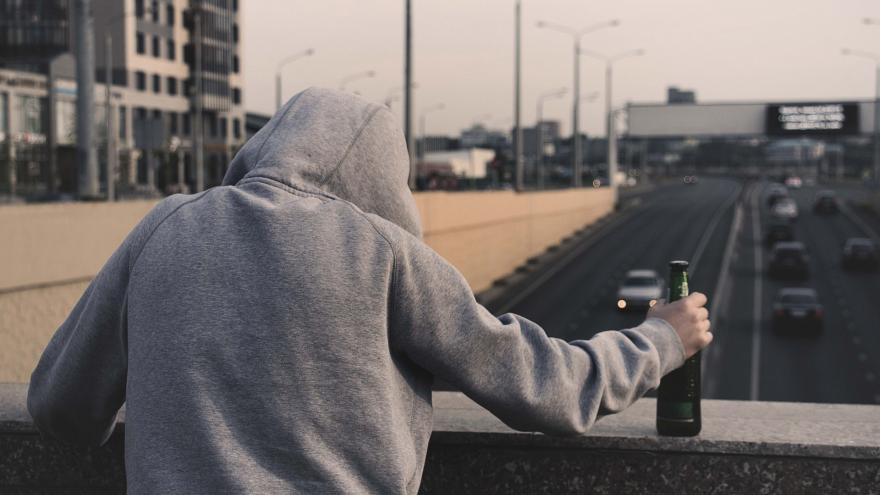 jóven mirando tráfico desde un puente con botella en la mano