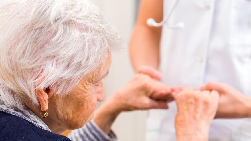 Anciana sostenida por un sanitario por las manos