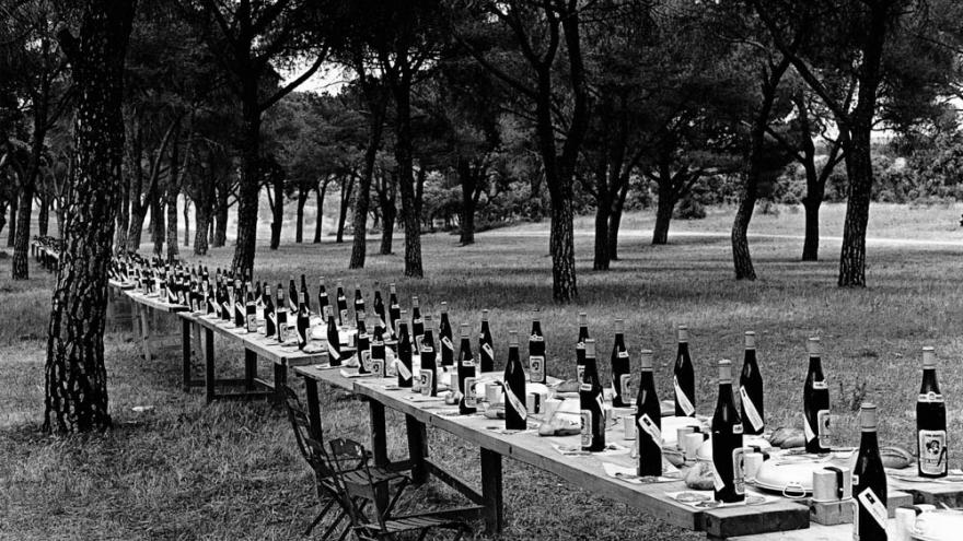 Ramón Masats. Casa de Campo. Madrid, 1958. Colección Museo CA2M Foto en blanco y negro con mesas plegables puestas en hilera con botellas encima
