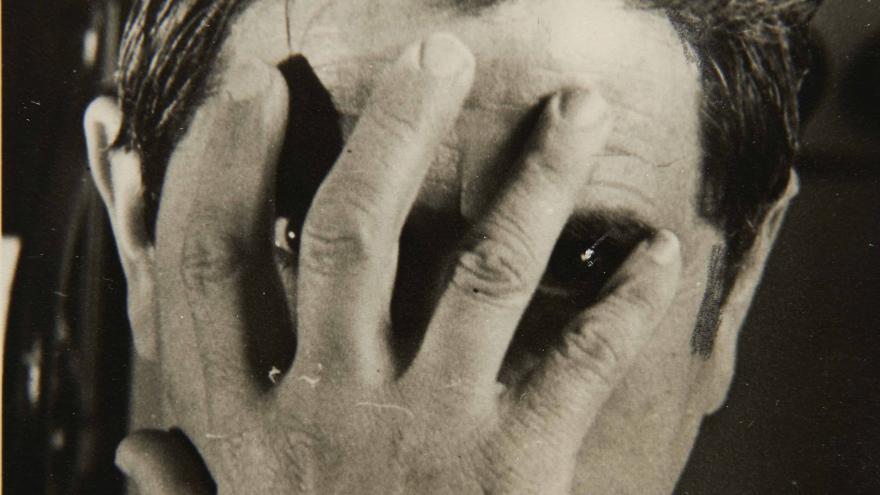 Fotografía en blanco y negro de un hombre ocultándo su rostro con una mano
