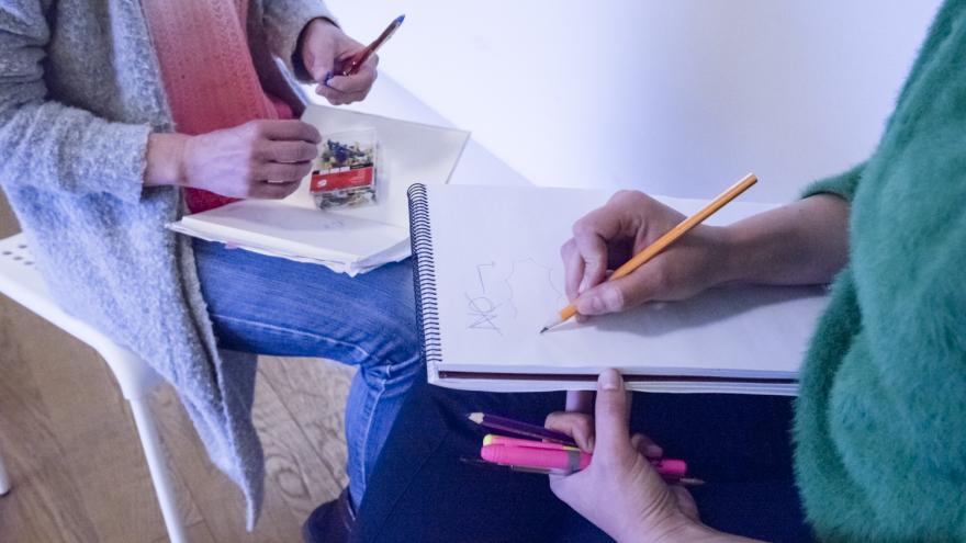 Dos chicas sentadas, enfrentadas, apuntando notas en sendos cuadernos