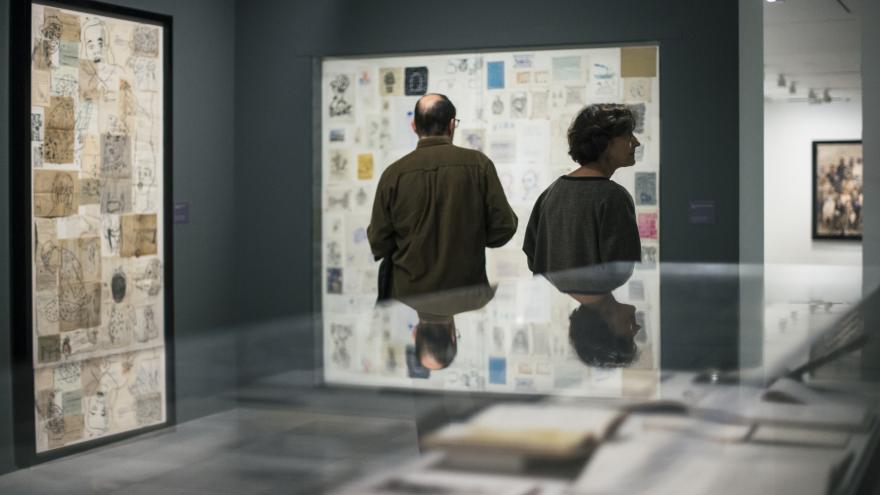 Dos visitantes observando dibujos realizados por Carmen Calvo
