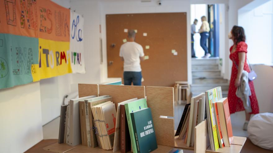 Sala de exposiciones con una estancia llena de libros y paneles con recursos educativos