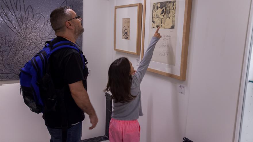 Un hombre y una niña visitando una exposición