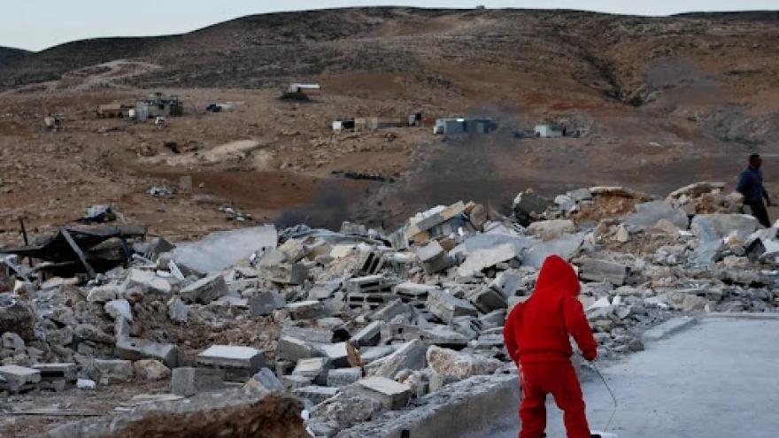 niño con abrigo rojo pasea por ruinas de Gaza