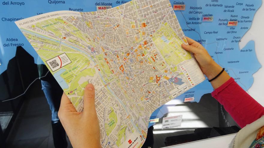 Usuaria de las oficinas de turismo observa un plano de la ciudad de Madrid