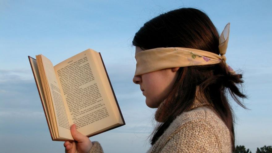 Joven con libro y venda en los ojos