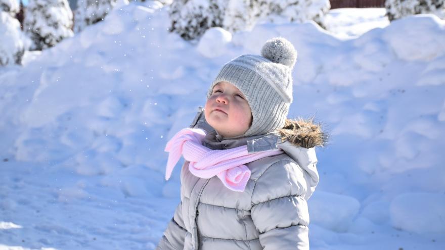 Niño con gorro de pie en la nieve 