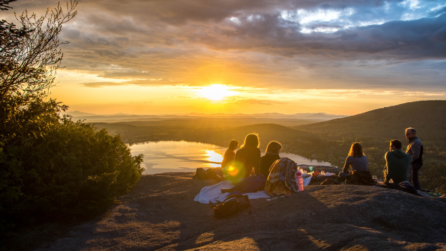 Un grupo de personas viendo el atardecer en un acantilado