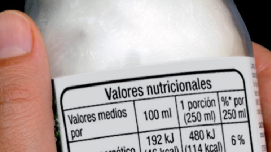 Etiquetado nutricional Manos con un yoghurt etiquetado con la información nutricional