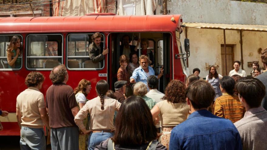 fotograma de un autobús rodeado de personas 