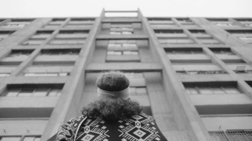 fotograma de una mujer de espaldas mirando hacia el final de un edificio alto