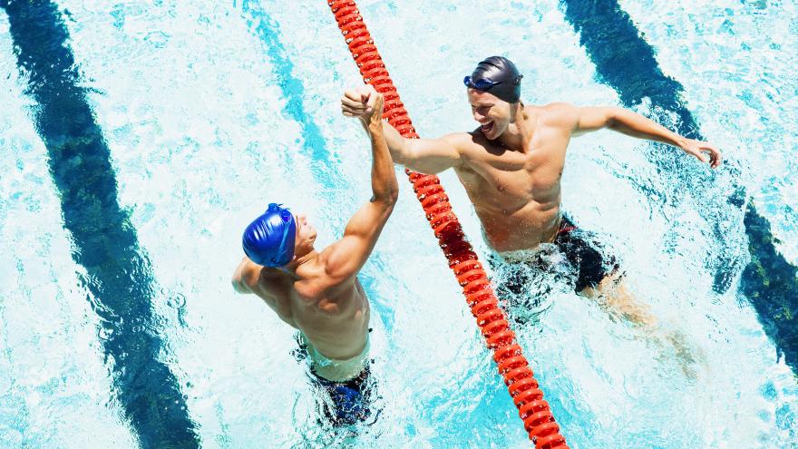 Dos nadadores en la piscina chocando manos