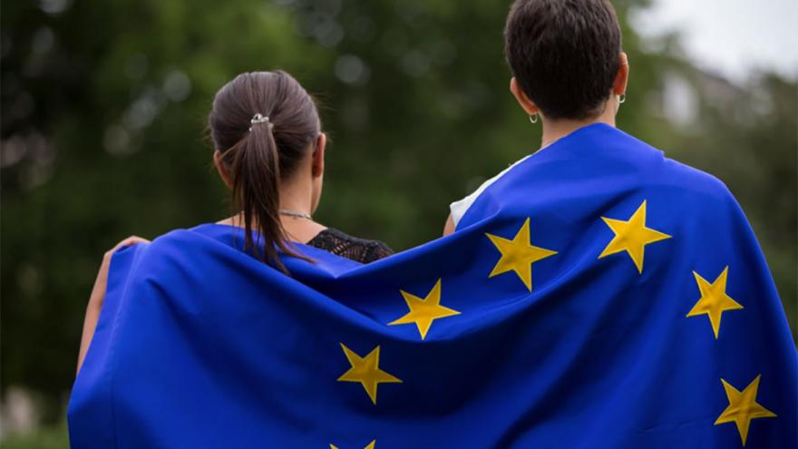Dos jóvenes con una bandera de la UE en sus espaldas