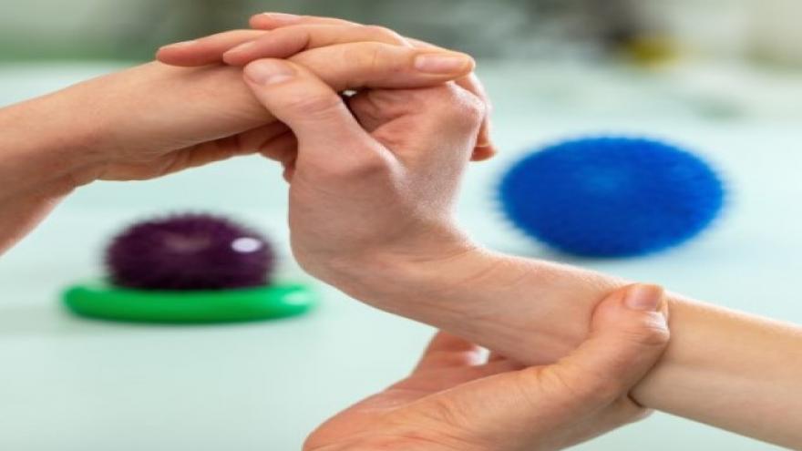 Terapeuta ocupacional movilizando mano de una paciente
