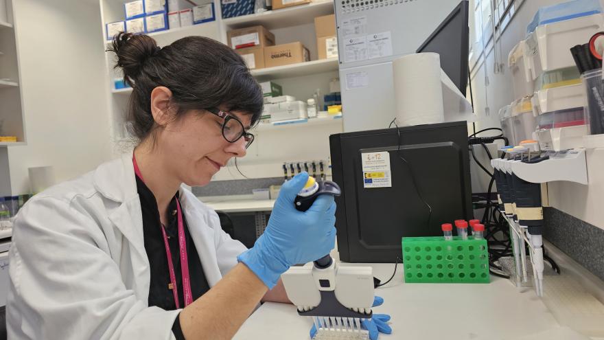 mujer con bata blanca con pipeta en laboratorio