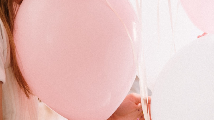 Imagen de persona con globos de color rosa y blanco