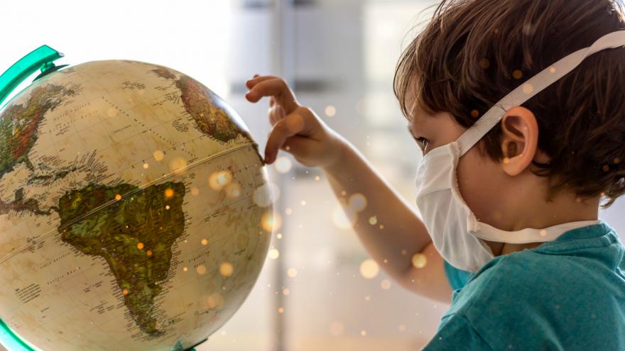 foto de un niño con mascarilla tocando un globo terráqueo