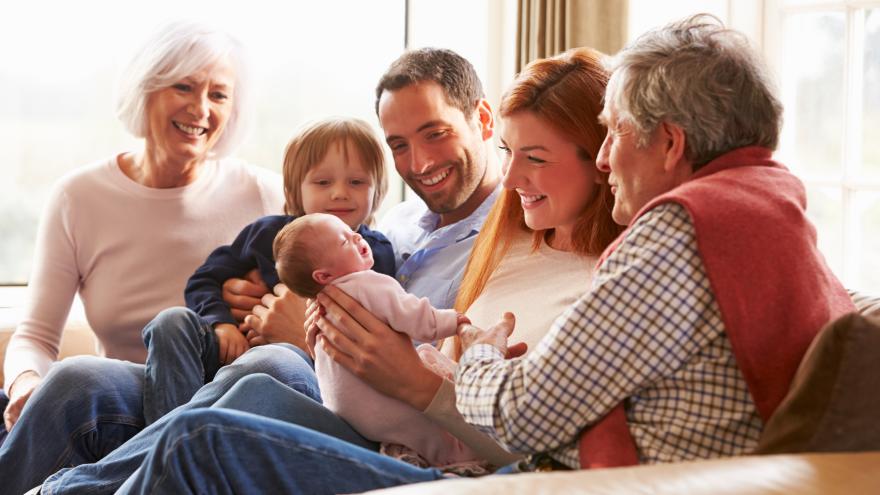 familia en sofá portada IG vacunas abuelos, padre, madre, niño pequeño y bebé sentados en un sofá