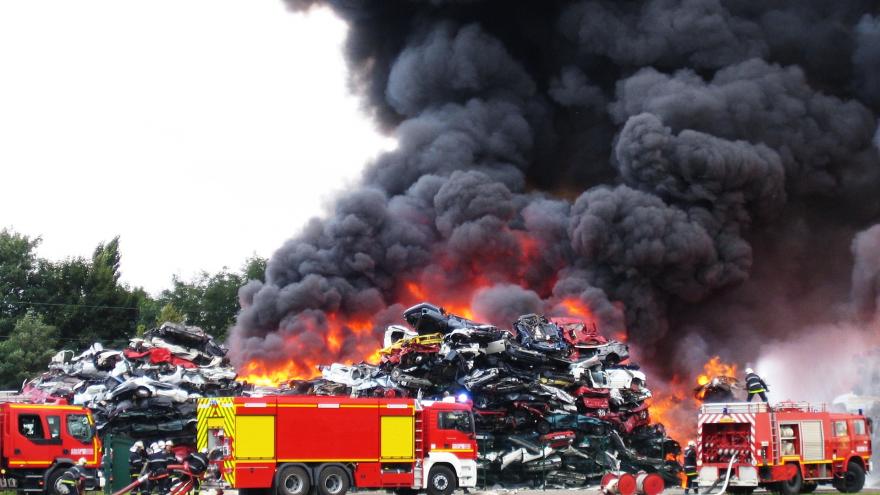 Bomberos apagando un incendio en un desguace de coches con mucho humo