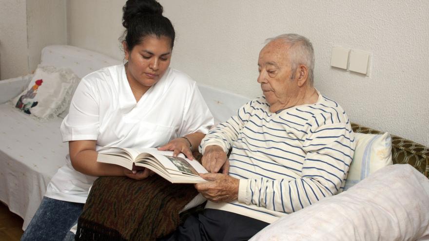 Hombre mayor y cuidadora leyendo juntos