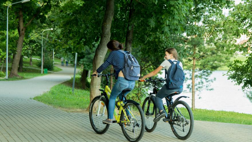 Formación con municipios Dos chicas en bici por zona ajardinada