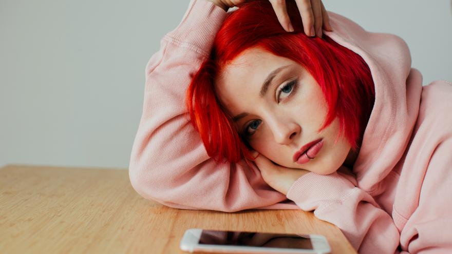 chica con pelo rosa apoyada en mesa con el brazo 