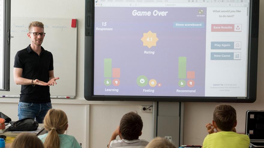 Profesor explica a los alumnos con ayuda de una pizarra digital