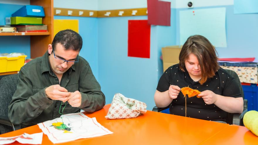 Personas con discapacidad intelectual tejiendo ropa con lana en una guardería
