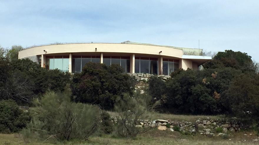 Fachada circular del edificio con cristalera y muro exterior con vegetación