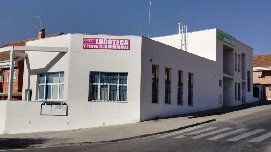 Casa blanca con ventanas y rótulos verde y rosa