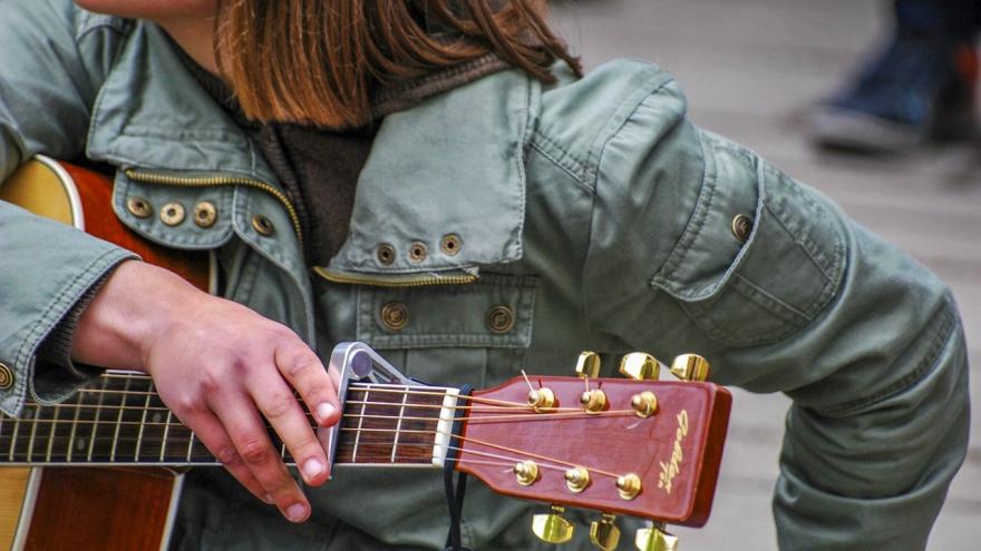 Mujer con la mano puesta en una guitarra