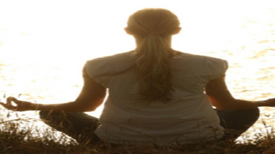 Mujer meditando sentada mirando al sol
