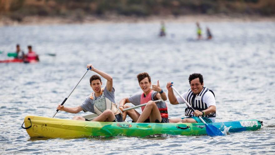 3 jóvenes remando en una piragua en un lago