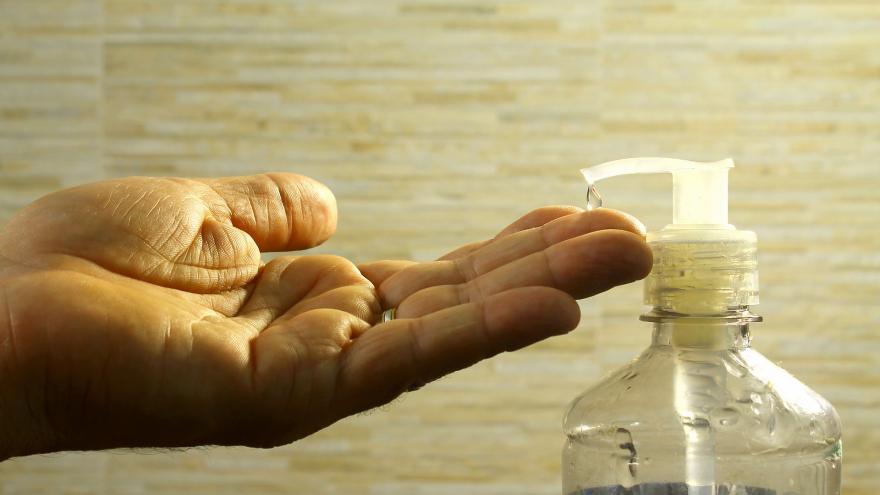 mano de hombre abierta para recoger una gota de gel de un dispensador