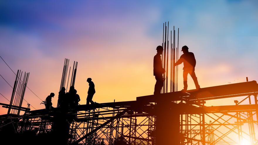 Obreros a contraluz sobre forjado de obra trabajando ferralla 