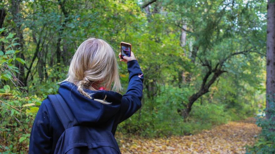 chica de espaldas haciendo un selfie en el campo