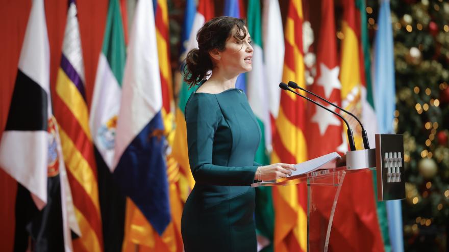 La presidenta con un vestido verde delante de las banderas en el acto