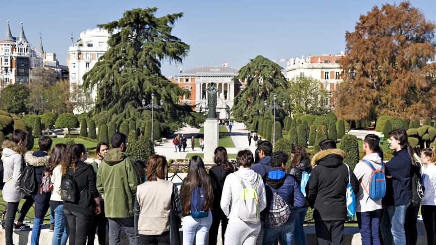 grupo de gente en una visita guiada con jardines al fondo